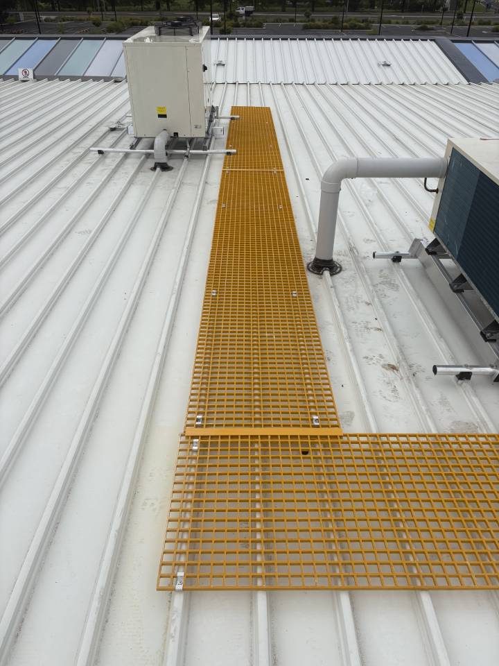 Yellow safety walkways and a metal access ladder installed on a commercial roof.