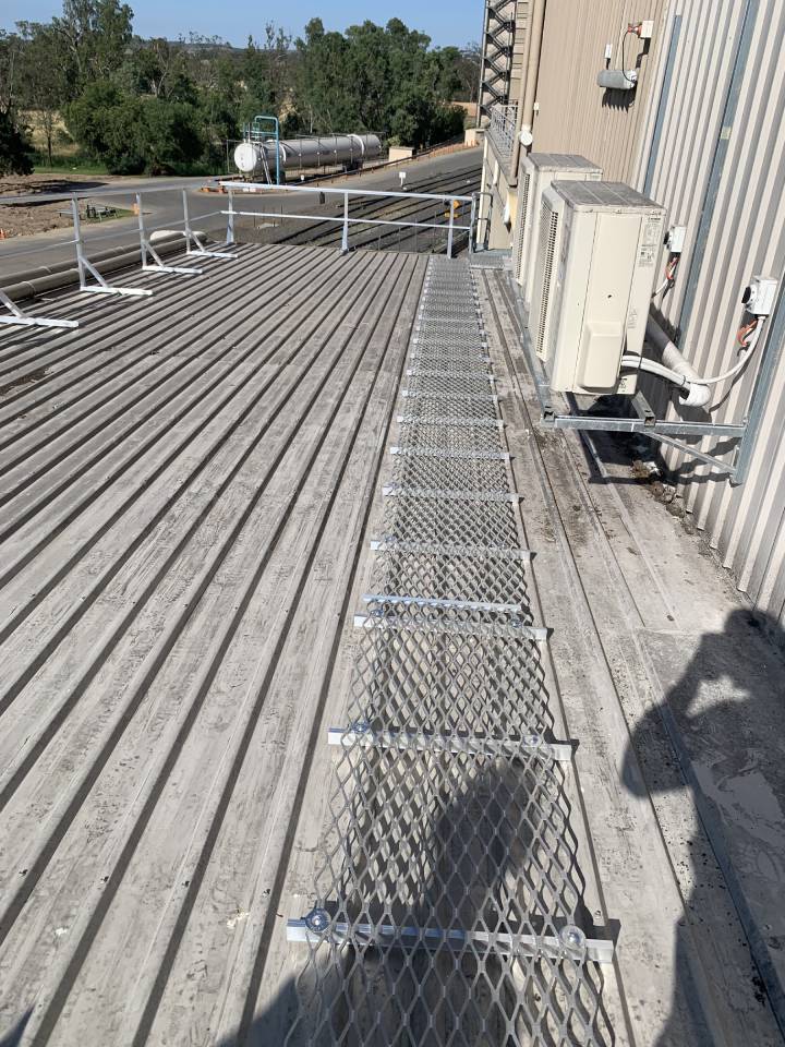 White corrugated metal roof featuring industrial HVAC units and safety equipment.